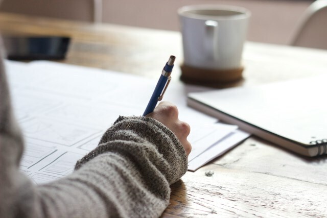 A person with a pen and writing on the paper.